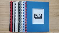 Eight coil-bound booklets in different color covers, including blue booklet marked Top Secret Consumertronics B20.
