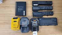 Seven battery packs including DeWalt 20V MAX XR, Ridgid 18V, and HP laptop batteries displayed on wooden surface