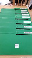 Eight green folders labeled from A to H containing ICs on conductive sheets, arranged on a flat surface.