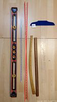 Complete lot items on floor: Black & Decker level, red flexible curve ruler, two wooden curved rulers, blue T-square