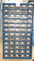 Front view of blue metal cabinet with multiple rows of labeled drawers containing resistors, visible resistor values on labels from 10R to 820K.