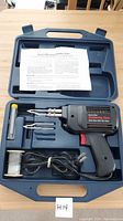 View of complete soldering gun kit including gun, solder wire spool, tips, and instruction manual in blue molded plastic case.