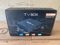 Front of closed black MXQ Pro TV Box packaging showing CPU 64 bit, H265 video codec, CPU 4 cores, 4K UHD labels.