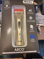Front view of Wahl Arco cordless clipper in original box showing champagne colored clipper with red blade and Wahl branding.