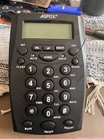 Front view of AGPtek call center dial pad telephone with visible LCD screen and control buttons including numeric keypad and function keys.