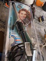 Front view of Conair curling iron in sealed package showcasing barrel and clamp, multi-layer technology info, model with curly hair.
