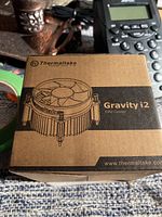 Front of the brown box showing Thermaltake Gravity i2 CPU cooler branding with line drawing showing the cooler design.