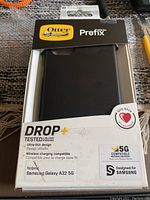 OtterBox Prefix Series black case in original packaging, compatible with Samsung Galaxy A32 5G, showing drop protection and wireless charging compatibility features.