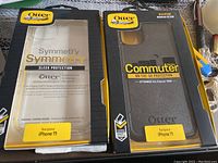 Both OtterBox cases in original packaging: Symmetry Series clear case and Commuter Series black case for iPhone 11.