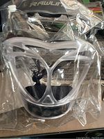 Clear Rawlings softball fielder's face mask in original packaging showing face shield and padding.