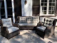 Front view of three-piece set on patio, showing sofa and two chairs with cushions.