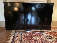 Front view of TV on rug with curved silver stand visible