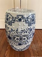 Front three-quarter view of the porcelain drum stool showing raised knop studs and floral scroll motifs