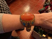 Bracelet shown on wrist at angled view highlighting large orange stone and filigree band.