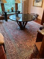 Overall view of Persian rug laid under round dining table in room