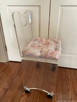 Side view of clear lucite chair showing curved profile and cushion