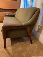 Left side angle of sofa showing teak frame and green upholstery