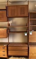 Frontal view of complete shelving unit including upper cabinet, two shelves, and lower drawer chest mounted on vertical metal frames