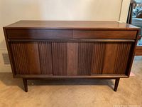 Front view of walnut mid-century modern credenza showing two top drawers and fluted tambour doors.