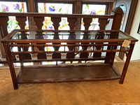 Front view of dark stained wood console table showcasing smoked glass top and woven cane shelf