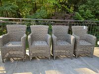 Front view of all four grey resin wicker chairs lined up on outdoor deck