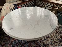 Overhead view of round white marble table top with gray veining