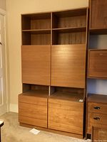 Front view of shelving unit showing four open upper shelves, two mid cabinet doors and lower drawers.