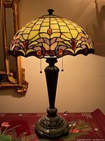 Frontal view of lit Tiffany style stained glass lamp showing full shade design and metal base