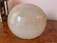 Frontal view of oval glass paperweight with gold aventurine bubbles