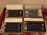 Four open cases showing four distinct sets of sterling cocktail spoons