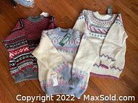 Three sweaters laid flat showing red, cream with pastel, and cream with burgundy patterns