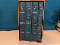 Four hardcover blue cloth books in slipcase, spines show title, author, and volume number in gold.