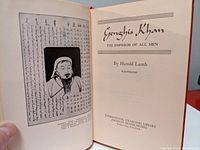 Title page of the book showing the title 'Genghis Khan: The Emperor of All Men' by Harold Lamb with an illustration and calligraphy on the adjacent page.