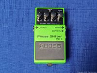 Front view of the Boss PH-3 Phase Shifter pedal showing the four control knobs and footswitch on a blue fabric background.