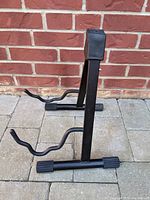 Side view of black guitar stand with two cradle arms for guitar and padded neck support.