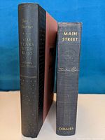 Side view of spines showing book titles, authors, and publishers. Condition visible shows wear and vintage status.