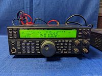 Front view of Kenwood transceiver showing display, keypad, tuning knob and attached cables.