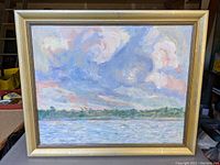 Frontal view of the original landscape oil painting showing the water, horizon, distant trees, and swirling cloud sky with visible brushstroke texture, in a gold wood frame.