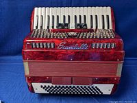 Front view of red pearloid accordion showing keyboard, grille, and Scandalli logo