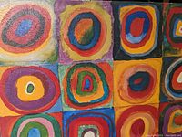 Close-up photo of abstract concentric circles on canvas showing texture and vibrant colors.