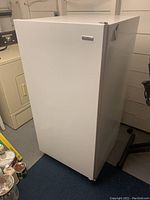 Front and side view of a white Kenmore upright freezer, showing overall good condition with minor scuffs