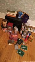 Full view of lot showing multiple vintage tobacco-related tins, cases, bags, and a black storage ottoman