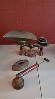Vintage weigh scale, bug sprayer, and iron grouped on table showing wear and details