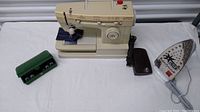 Singer Merritt 9608 sewing machine next to a green accessory case and Rowenta iron on a white surface.