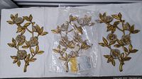 Three gold-tone floral wall hangings with detailed leaves and flowers placed side by side on a white background, showing overall condition and design