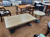 Rectangular coffee table and round side table placed on carpeted floor with other furniture in background.