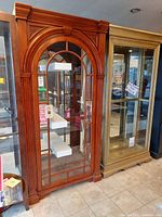 Front view showing arched mullioned glass door and overall cabinet form