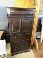 Front view of the tall wood dresser showing four drawers and the two-door cabinet.
