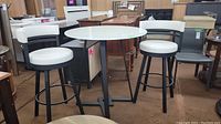 Full view of bar table with two stools on concrete floor