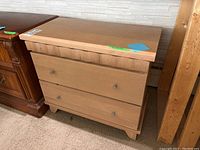 Front view of wood bedside table showing two drawers with metal pulls and scalloped detail below the top surface.